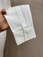White shirt cuff with button and pleated cuff placket detail.