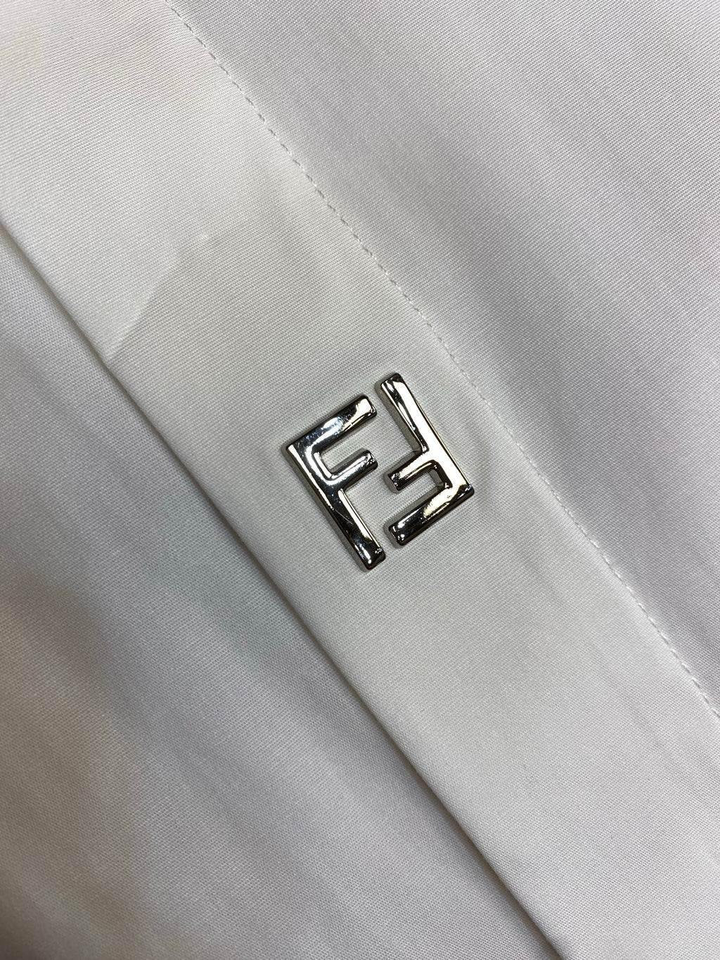 White shirt chest logo patch with outlined FF emblem stitching.