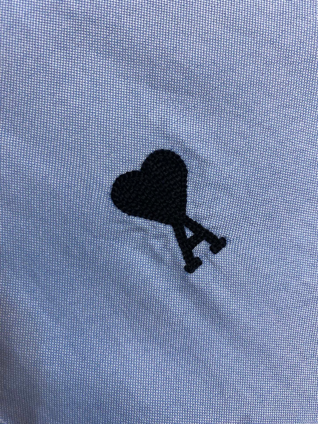 Black polo emblem on light blue button-up shirt fabric