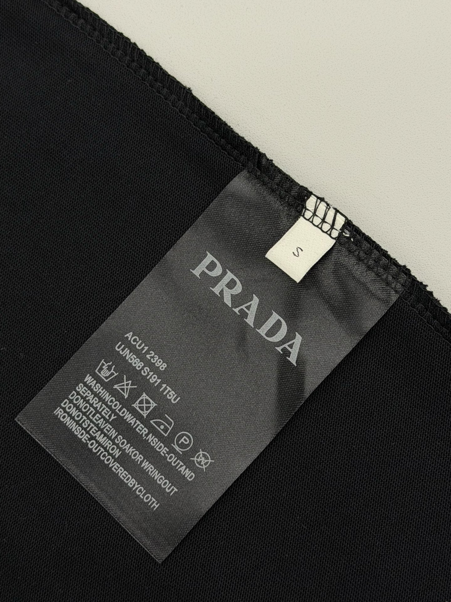 Black Prada T-shirt fabric tag with size and care instructions