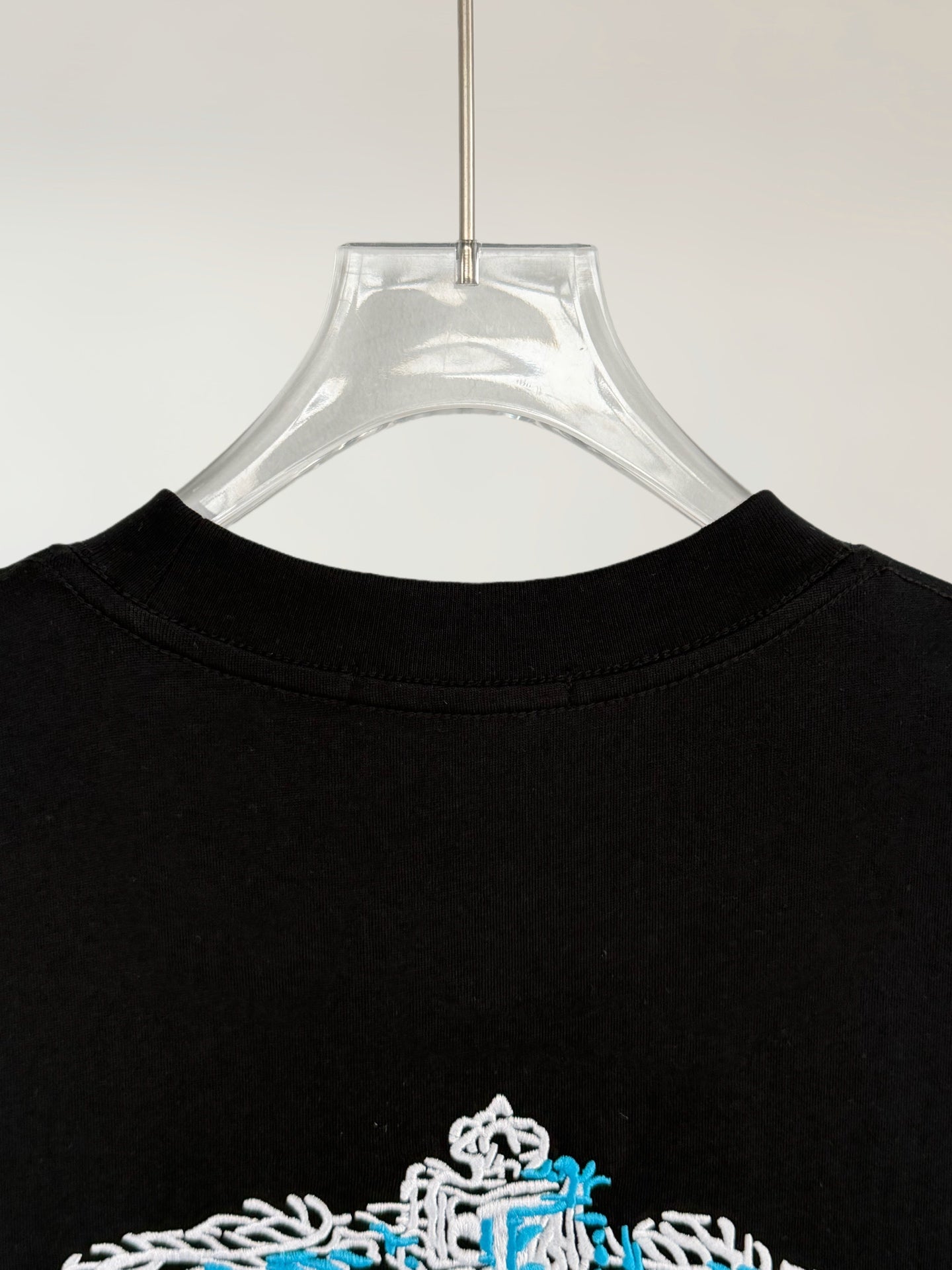 Prada Milano black T-shirt back neckline with partial white-and-blue crest graphic