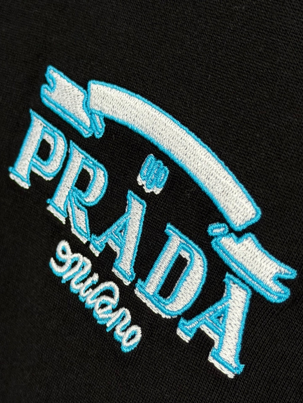 Prada Milano black T-shirt close-up of blue PRADA logo with Milano script