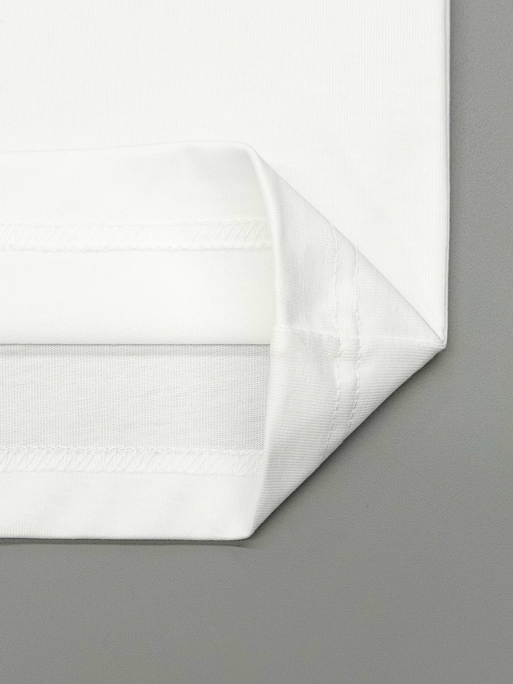 Folded white T-shirt fabric with smooth seams along the bottom hem