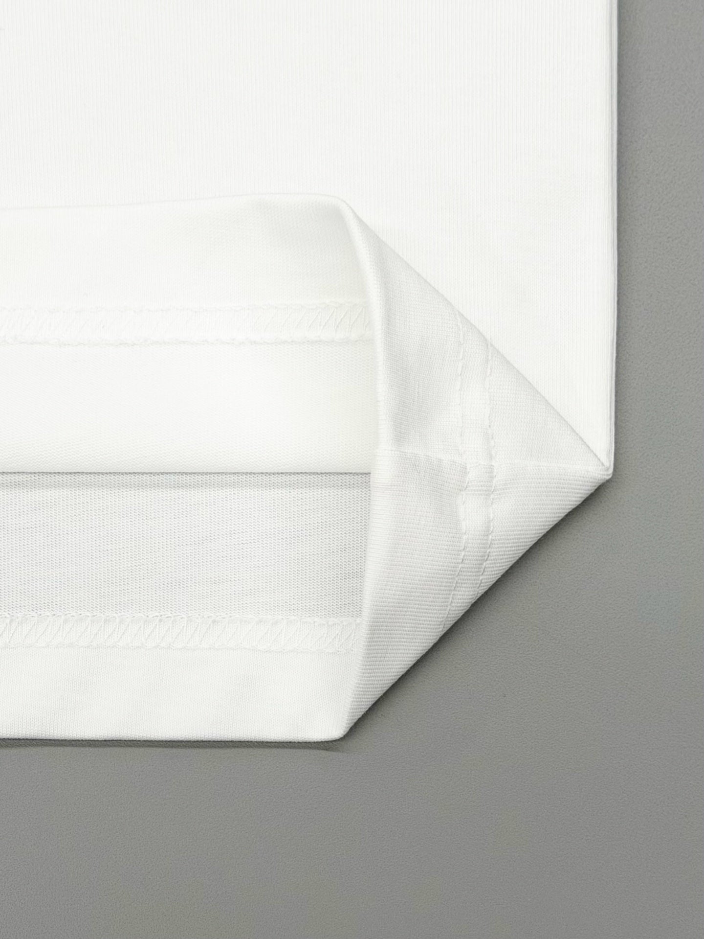Folded white T-shirt fabric with smooth seams along the bottom hem