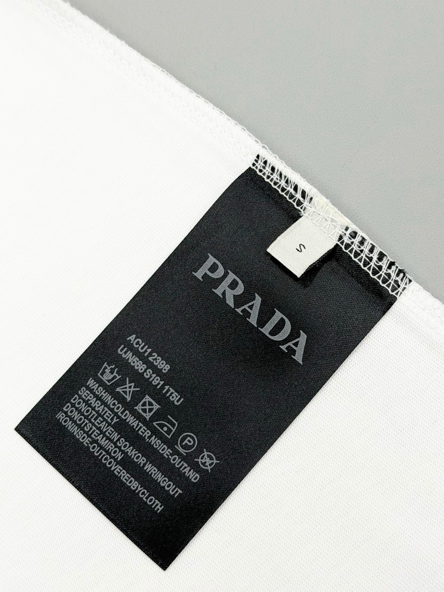 Black PRADA size and care label inside white T-shirt hem