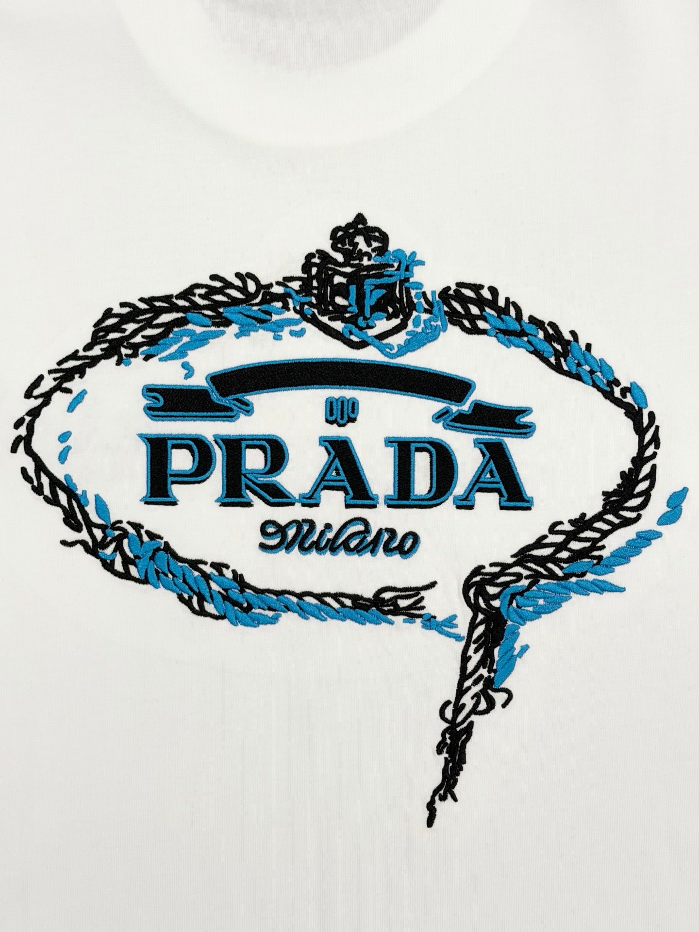 Embroidered PRADA logo crest with blue details on white T-shirt front