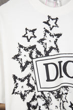 White short-sleeve T-shirt close-up showing black starburst print and partial Dior logo