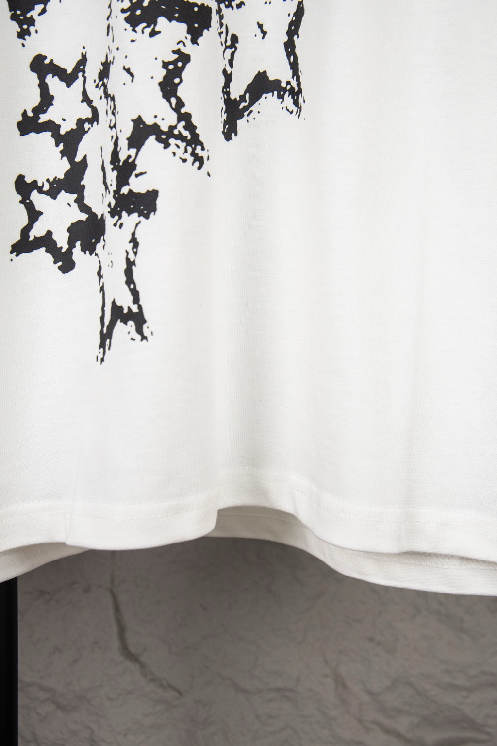 White short-sleeve T-shirt lower hem with black starburst print at upper left