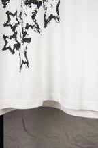 White short-sleeve T-shirt lower hem with black starburst print at upper left
