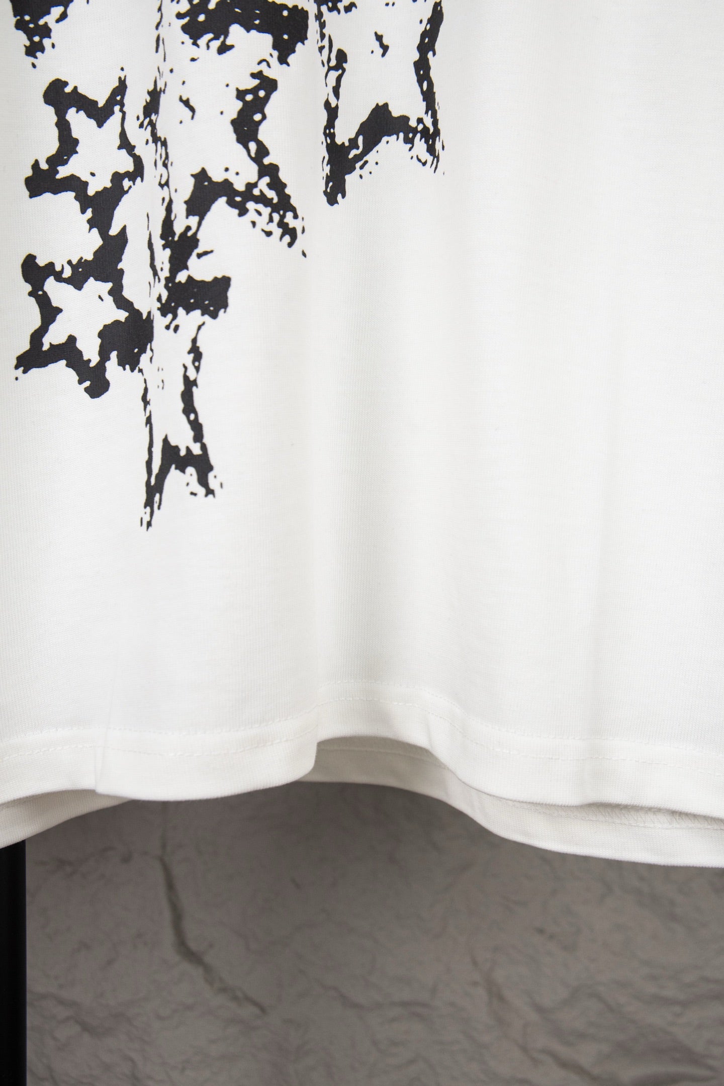 White short-sleeve T-shirt lower hem with black starburst print at upper left