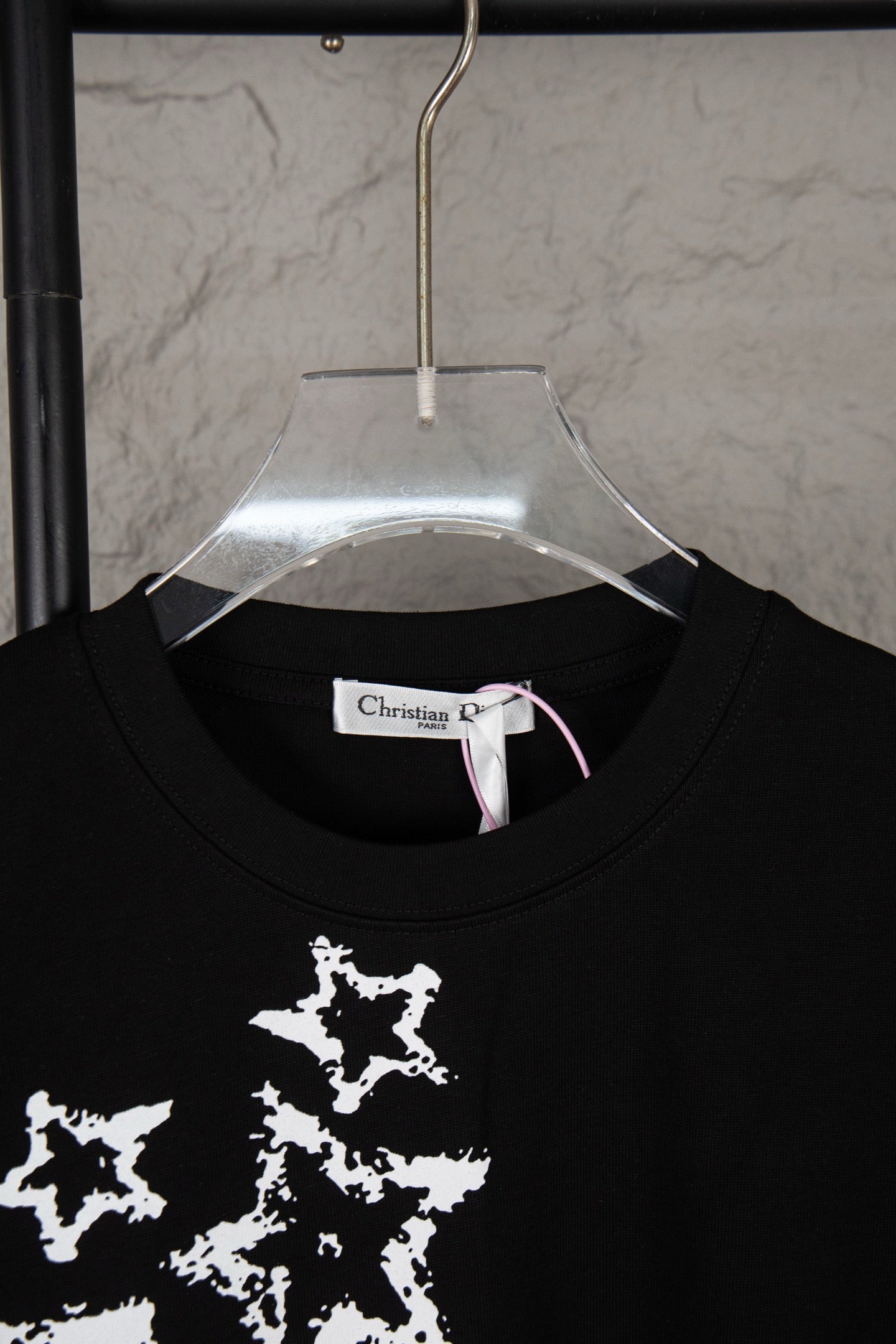 Black T-shirt neckline with white star print visible and Christian Dior neck label