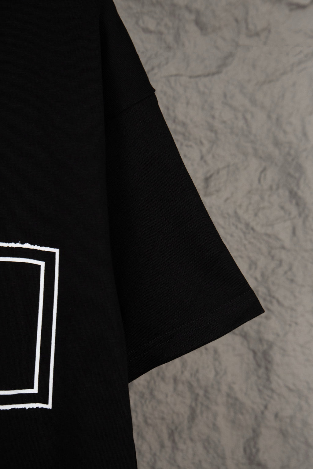 Black T-shirt sleeve with white outlined square graphic detail