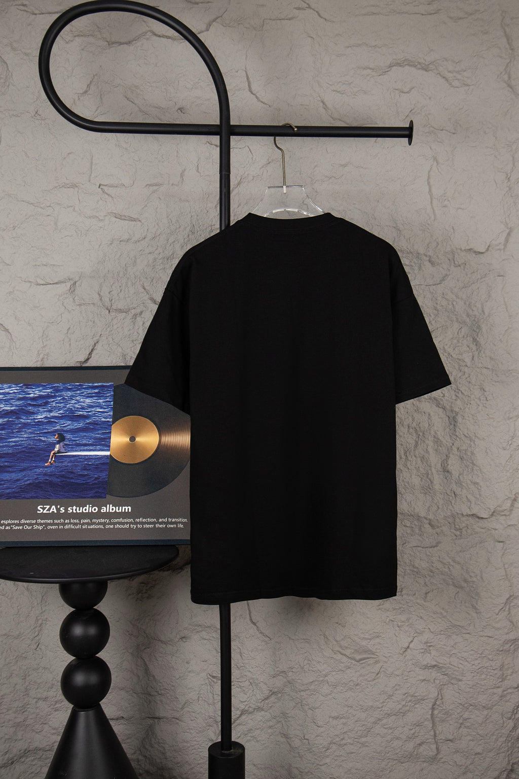 Black short-sleeve T-shirt with a plain back view hanging on clear hanger