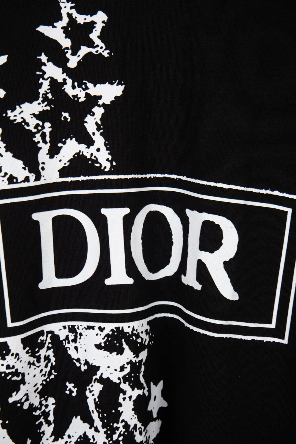 Black T-shirt close-up: white DIOR logo banner over starburst print