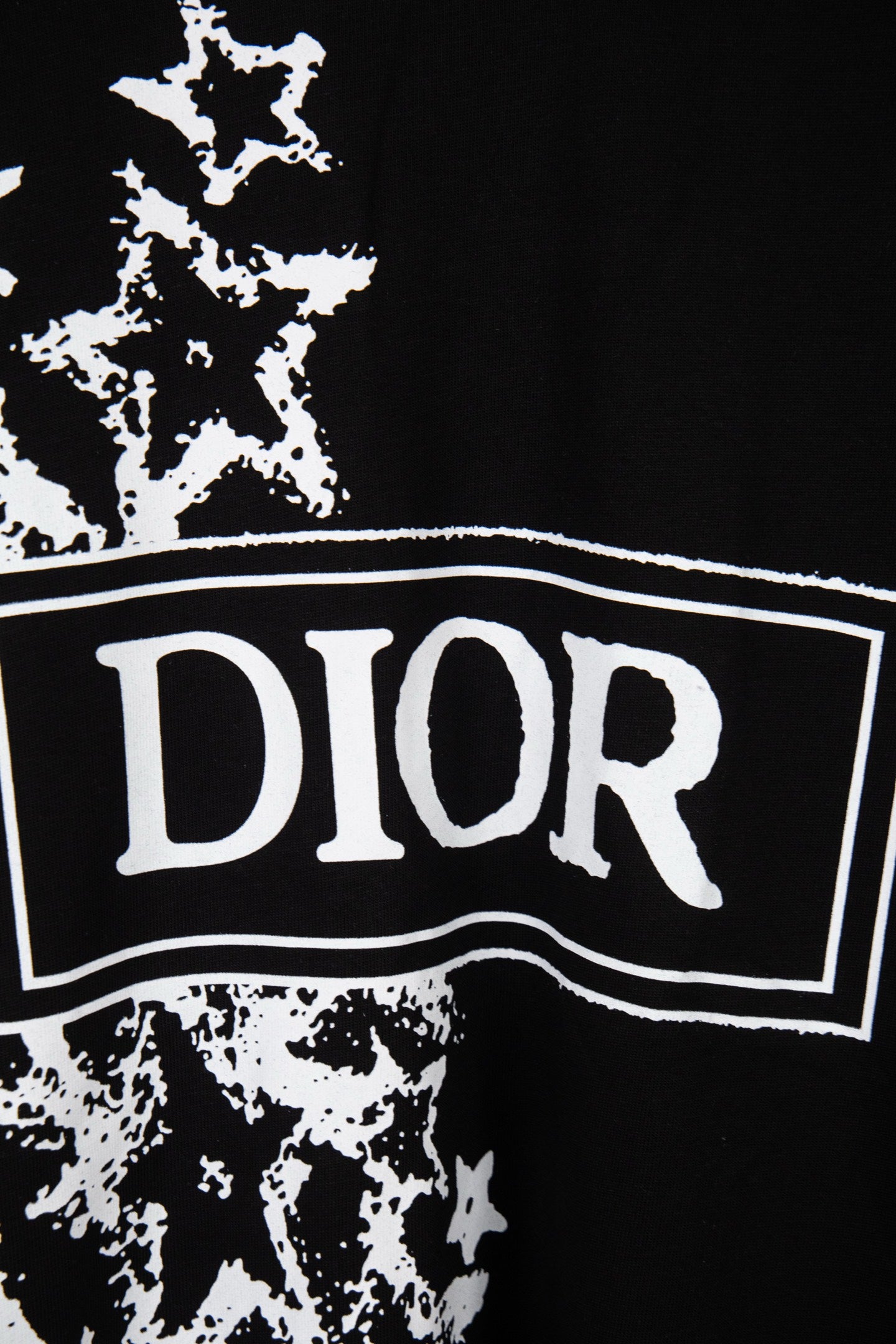 Black T-shirt close-up: white DIOR logo banner over starburst print