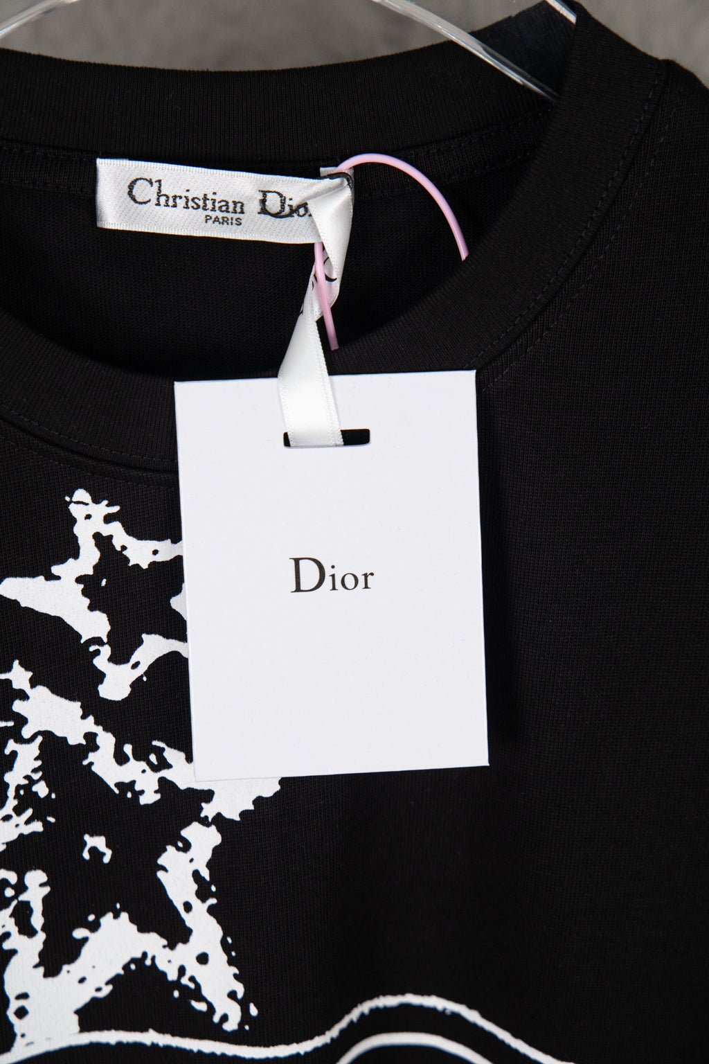 Black T-shirt with white star print and Dior brand hang tag at the collar
