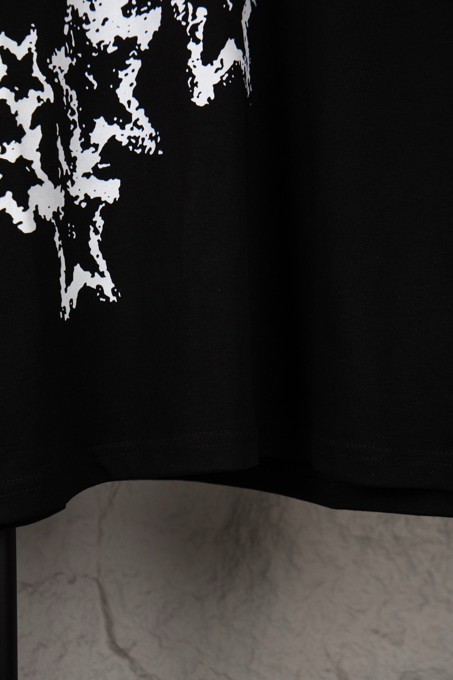 Black T-shirt lower hem with partial white starburst print