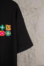 Black T-shirt with colorful embroidered emblems on left chest