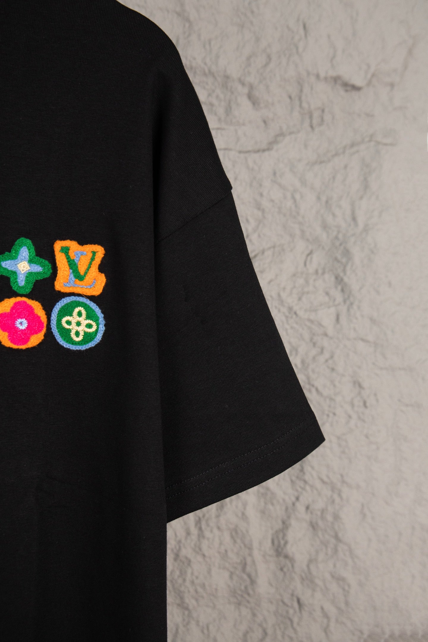 Black T-shirt with colorful embroidered emblems on left chest