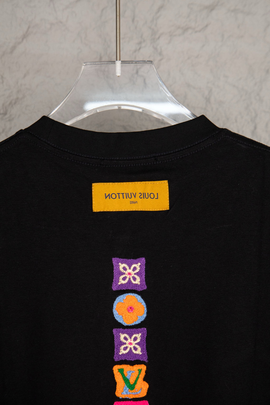 Black short-sleeve T-shirt with neck label and stacked multicolor icons on back