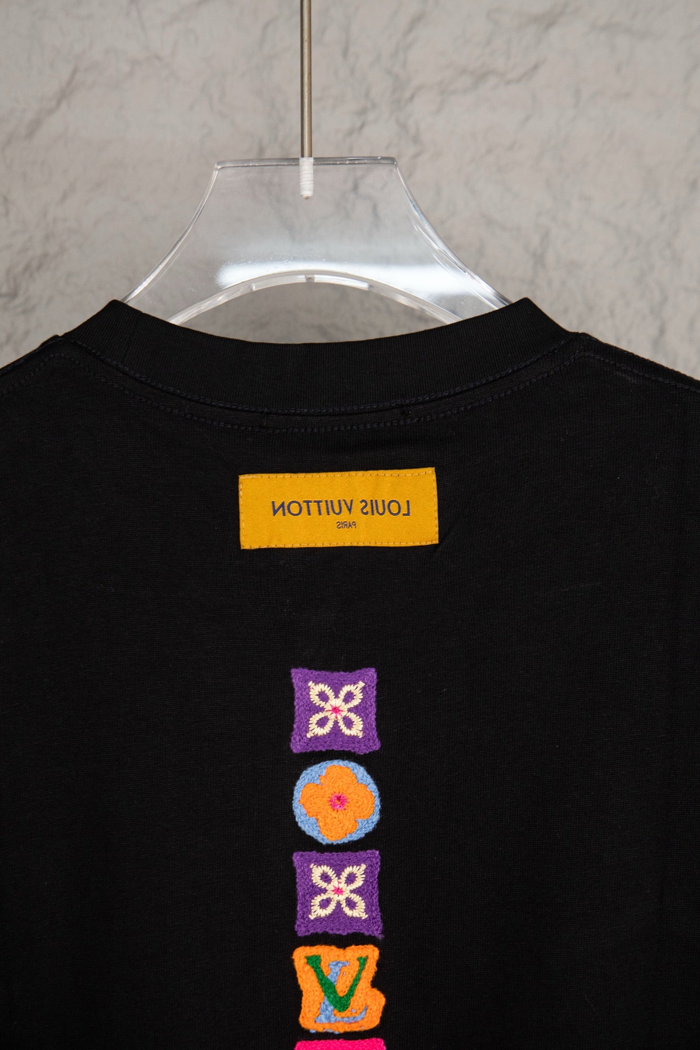 Black short-sleeve T-shirt with neck label and stacked multicolor icons on back
