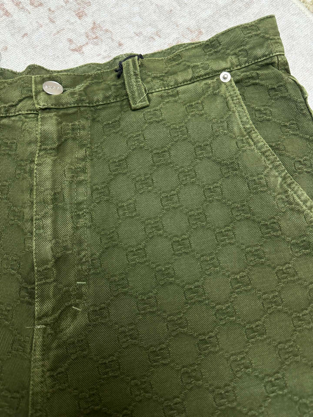 Green Gucci shorts waistband with button closure and stitched detailing.