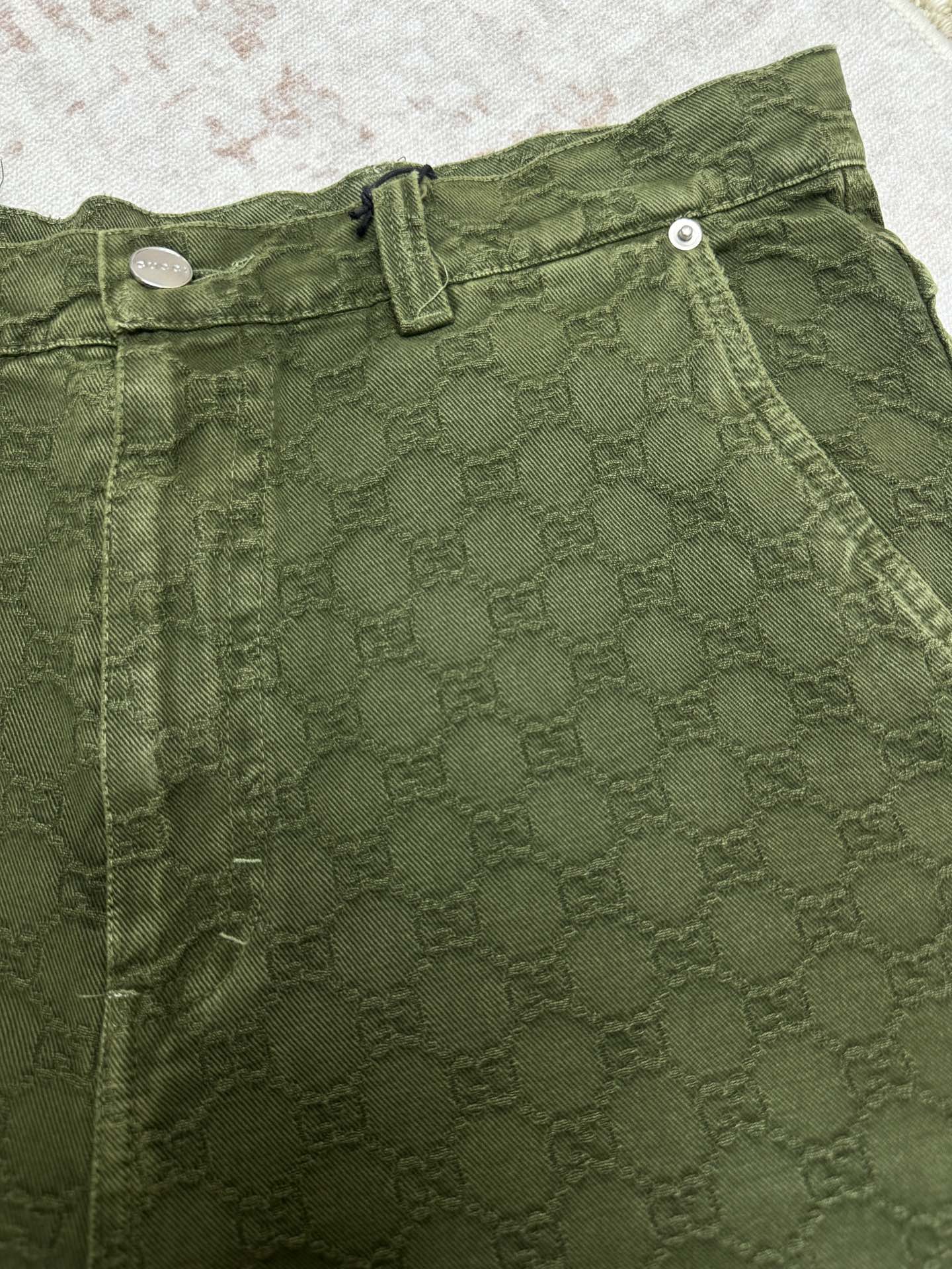 Green Gucci shorts waistband with button closure and stitched detailing.