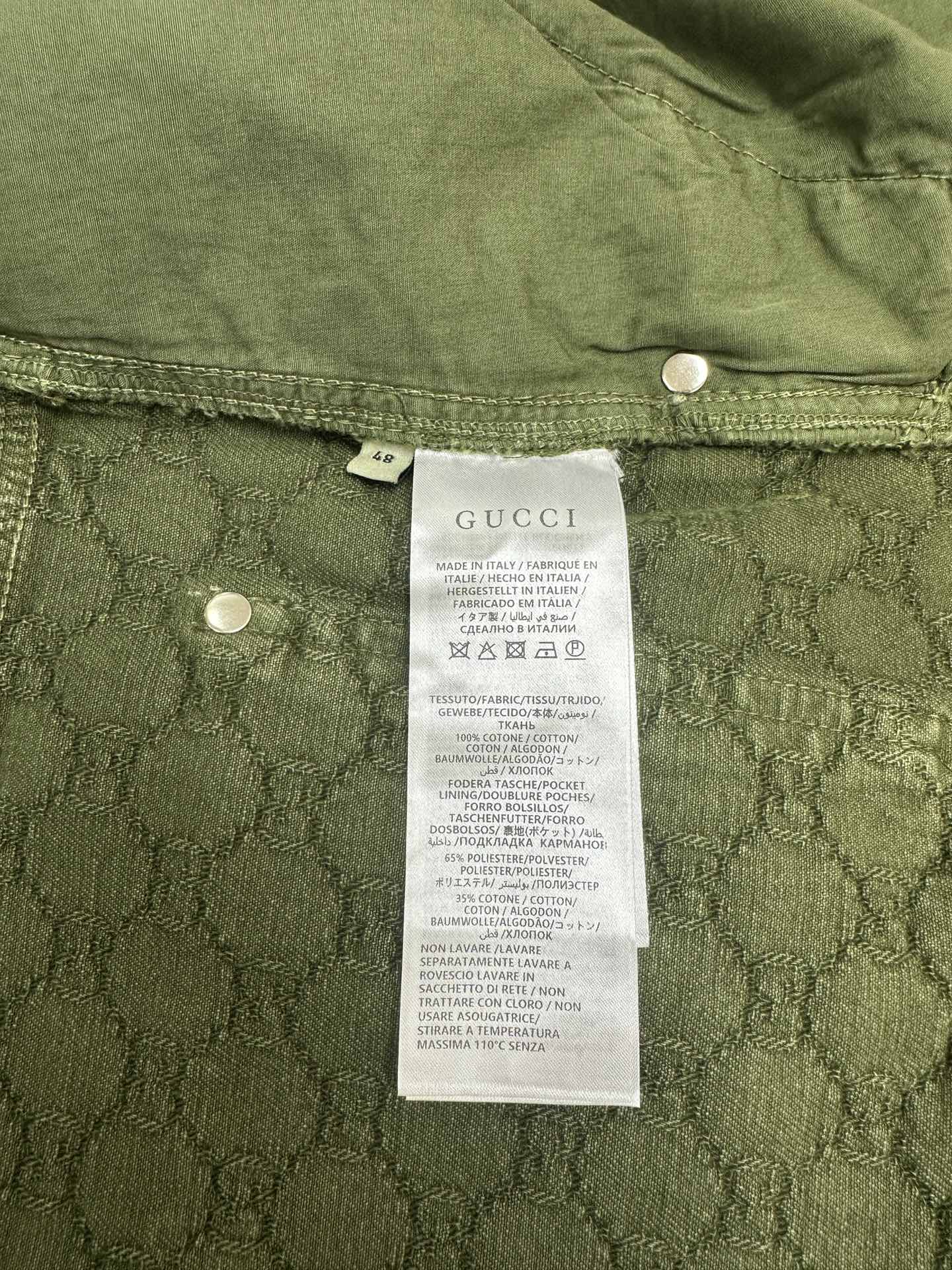 Green Gucci shorts showing care label and interior waistband buttons.