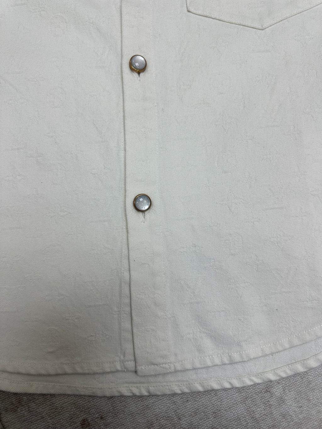 White button-up shirt front with two metal buttons on placket