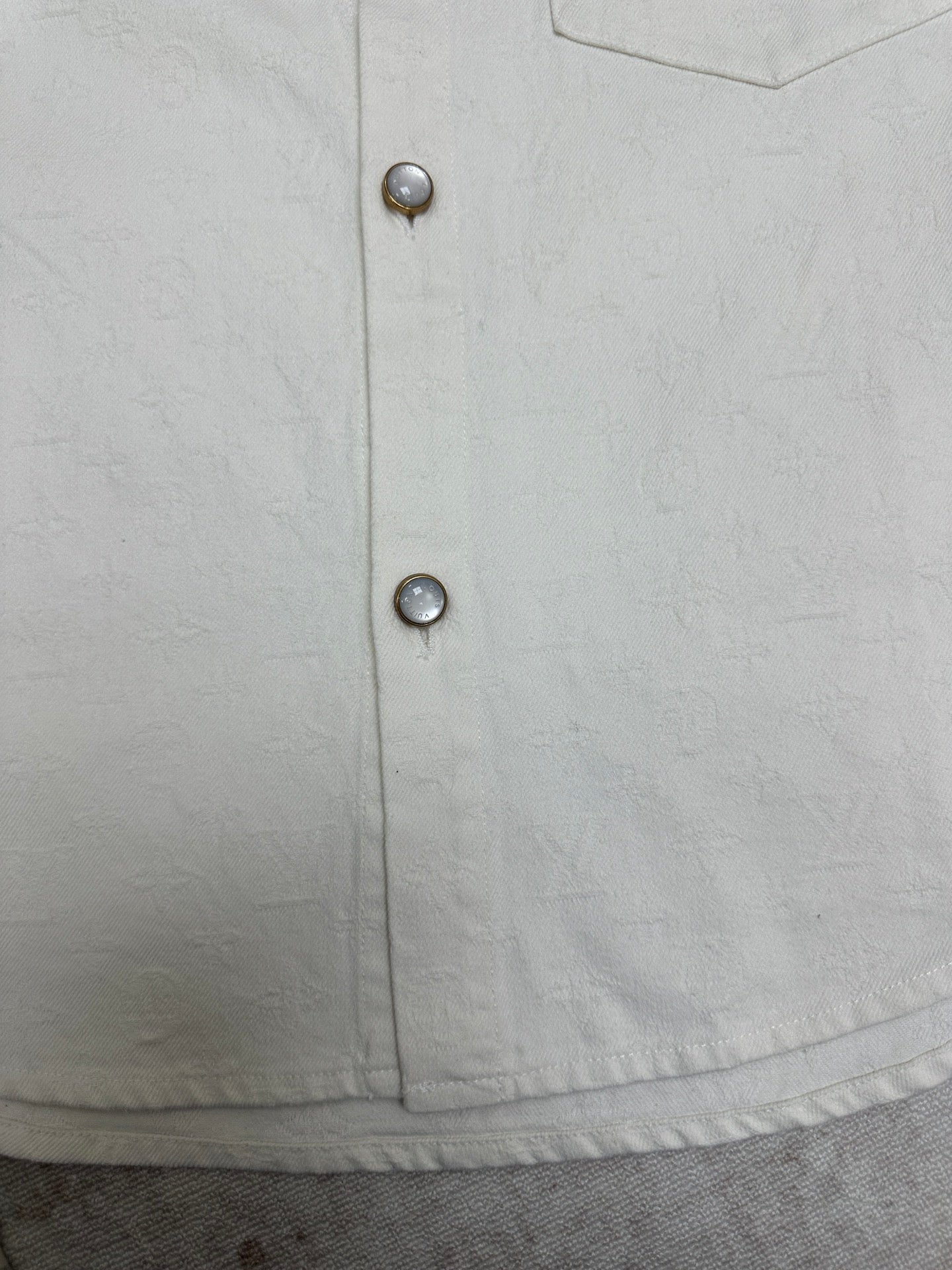 White button-up shirt front with two metal buttons on placket