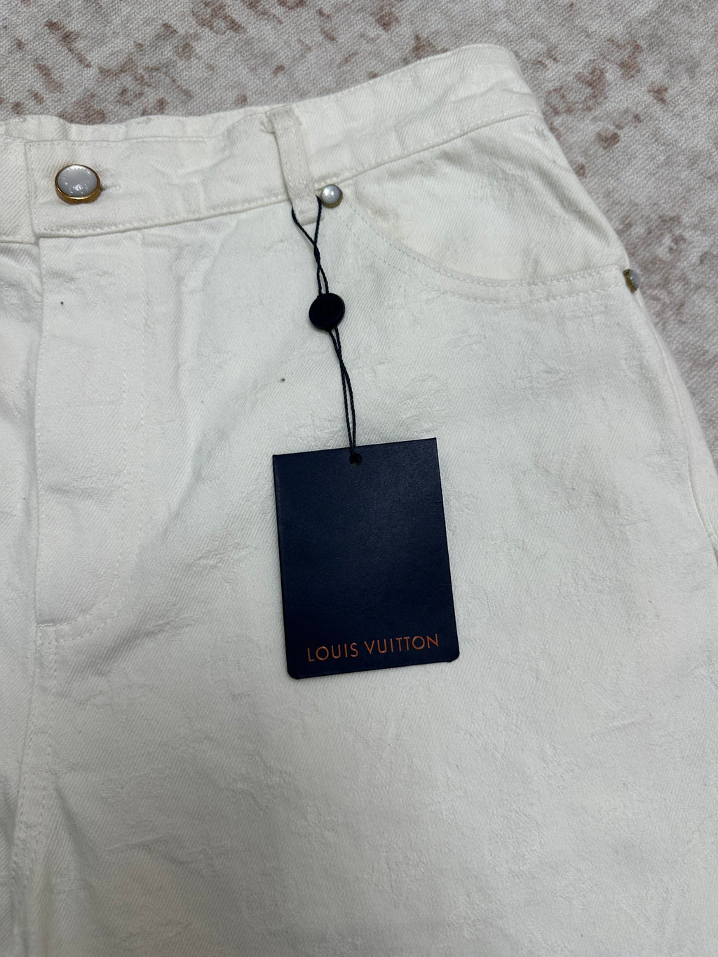 White shorts front with metal snap buttons and Louis Vuitton hang tag