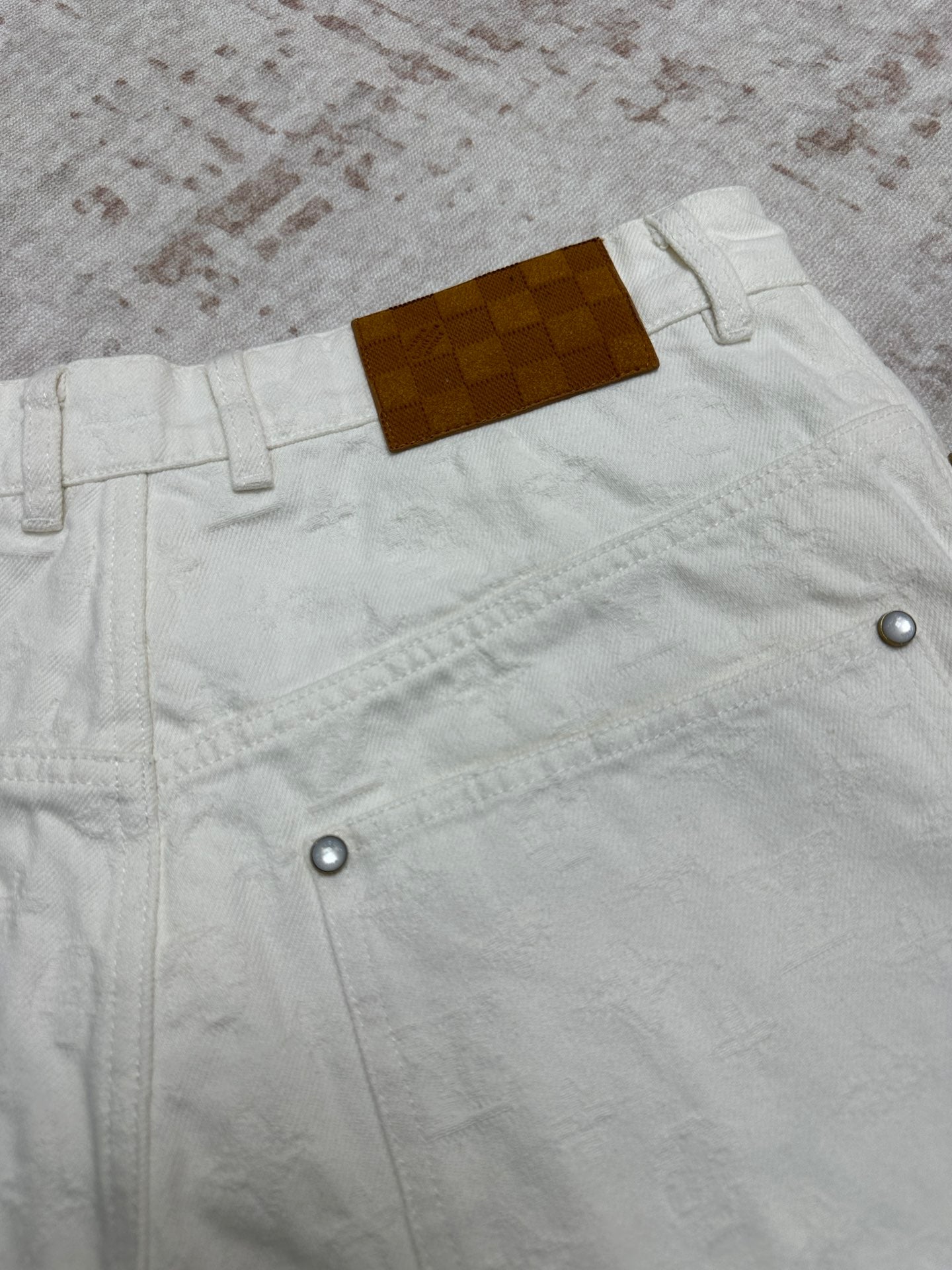 White shorts with belt loops and metal buttons, leather brand patch