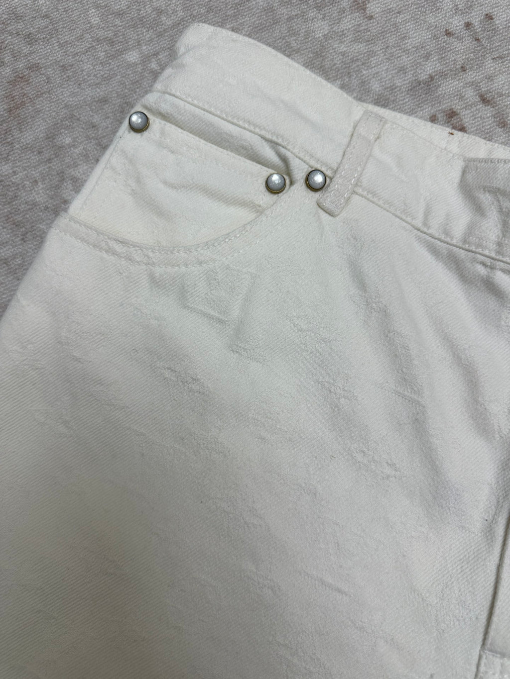 White shorts waistband close-up with metal button details