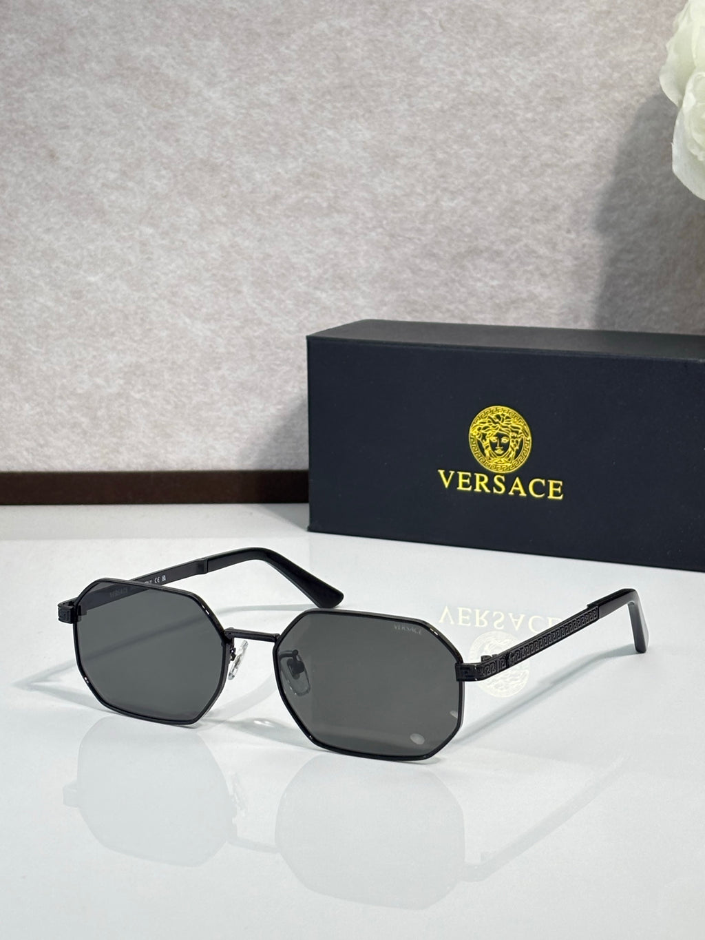 Versace sunglasses with black hexagonal frames and dark gray lenses.