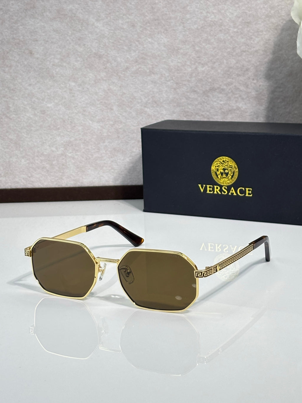 Versace sunglasses with gold frames and dark olive tinted lenses.