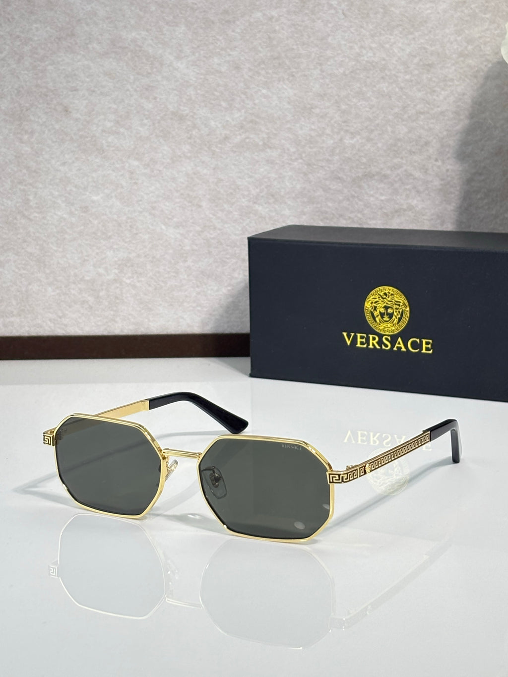 Versace sunglasses with gold frames and dark lenses with octagonal shape.