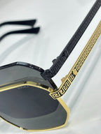 Versace sunglasses temple detail: black textured arms with gold accents and dark lenses.