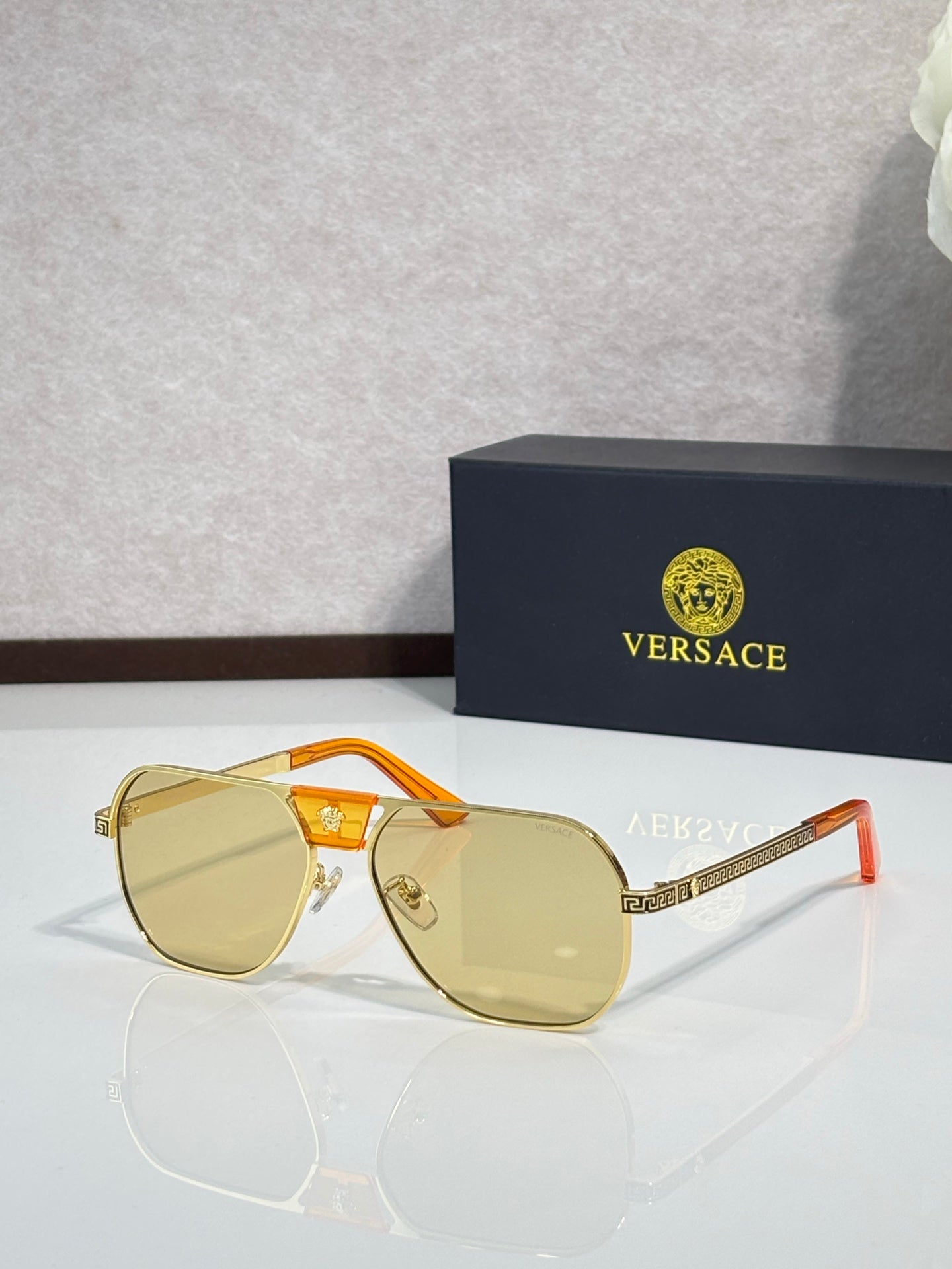 Versace sunglasses with light gold frame and amber tinted lenses, angular square design