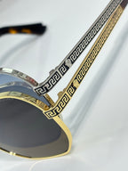 Versace sunglasses close-up: gold and silver Greek-key temple detailing with dark lenses
