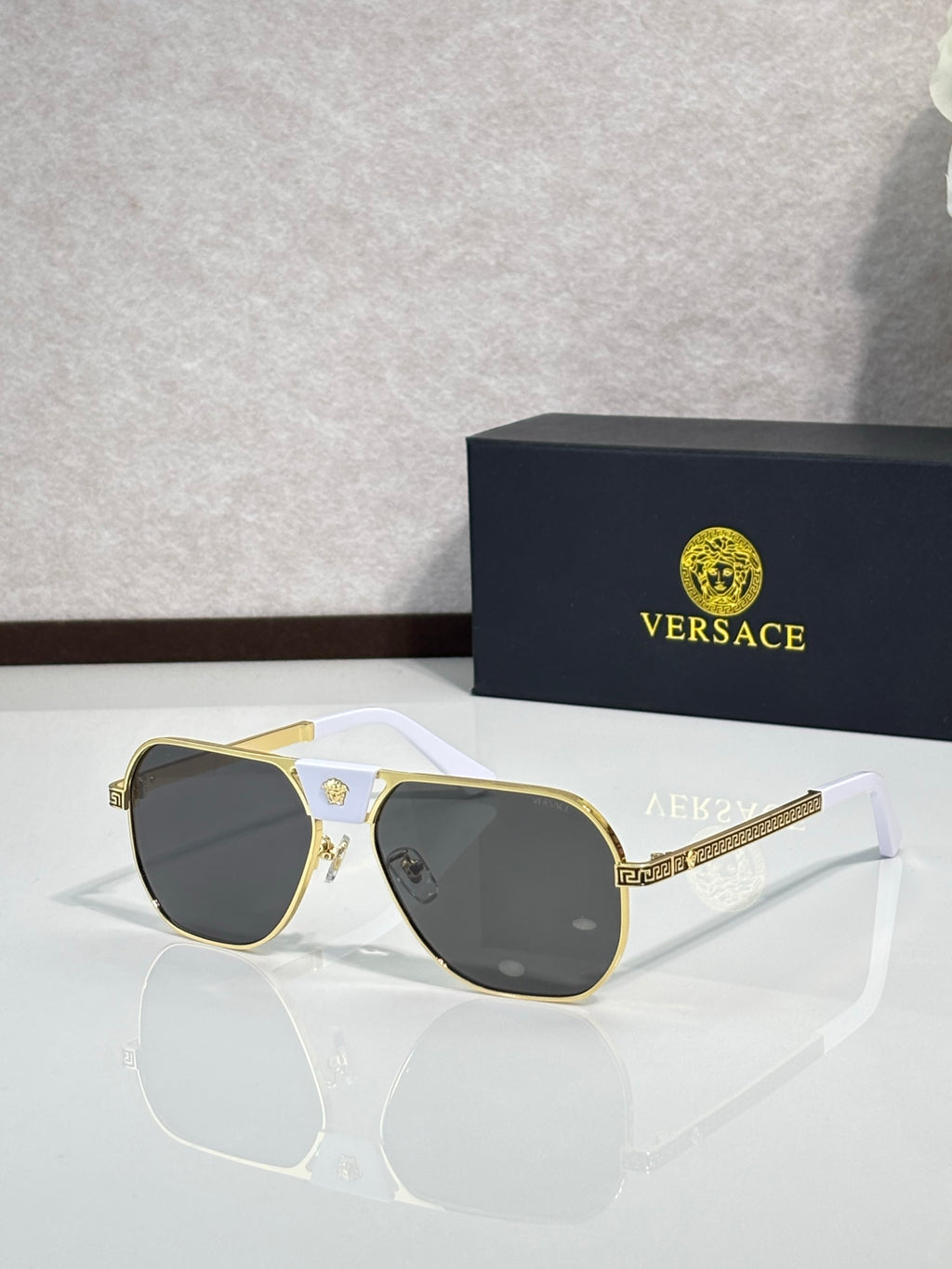 Versace sunglasses with gold frame and dark lenses, square shape with white arms