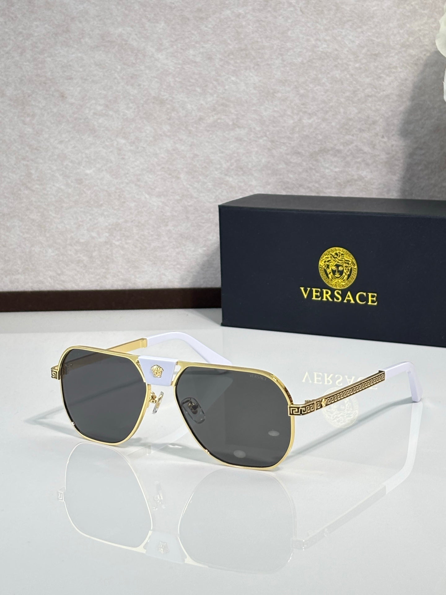 Versace sunglasses with gold frame and dark lenses, square shape with white arms