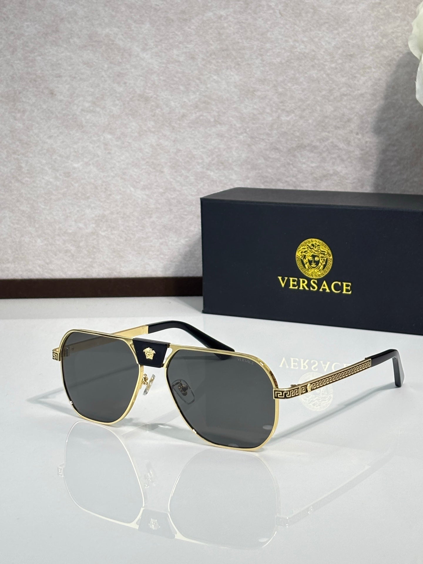 Versace sunglasses with gold frame and dark gray lenses, square aviator style