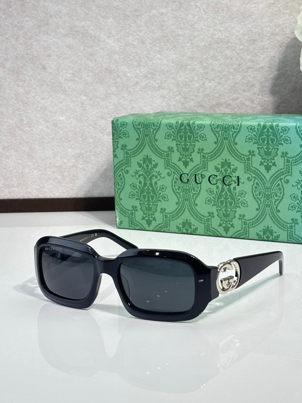 Gucci sunglasses, black square frames with dark lenses and silver-toned emblem.