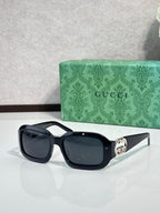 Gucci sunglasses, black square frames with dark lenses and silver-toned emblem.