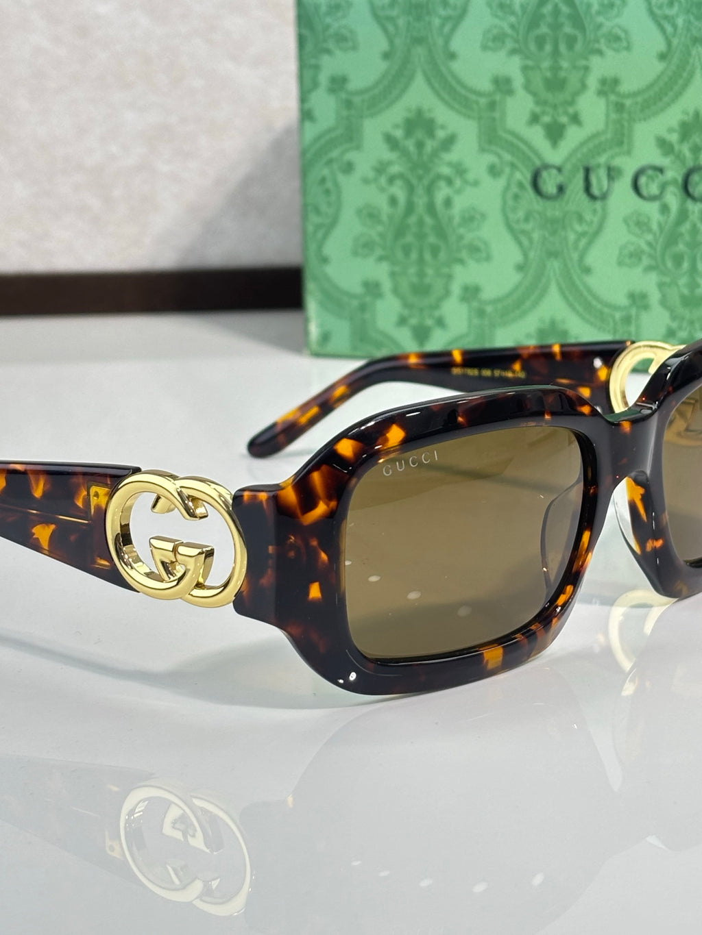 Gucci sunglasses, tortoise frame with gold GG logo on temple and amber lenses.
