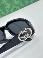 Gucci sunglasses, close-up dark frame with silver interlocking GG emblem on temple.