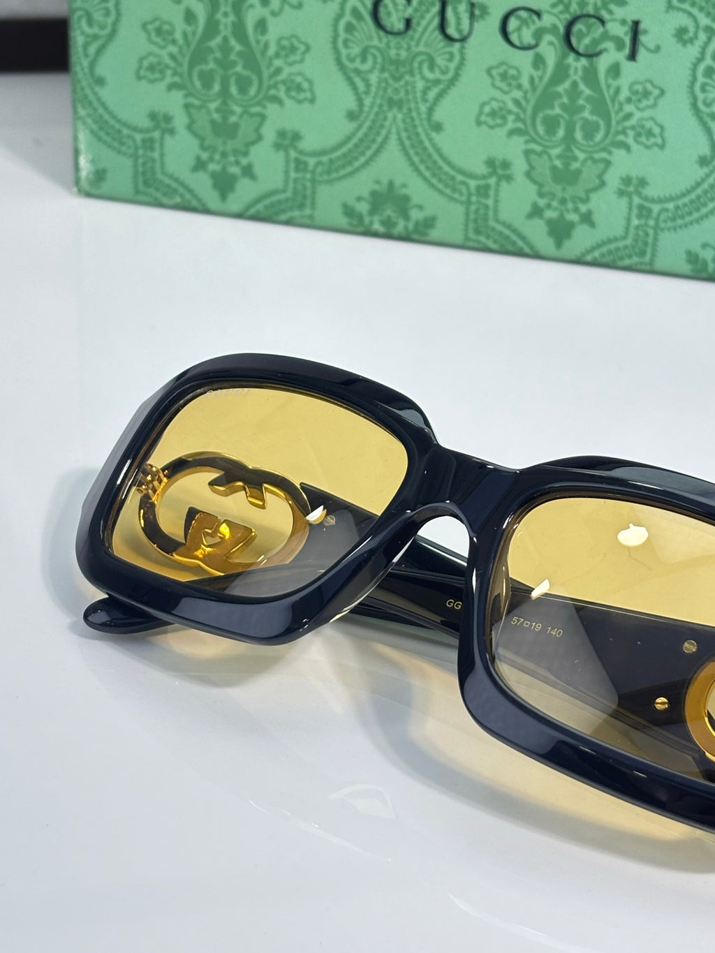 Gucci sunglasses, close view of tortoise frames with gold lenses and GG hardware.