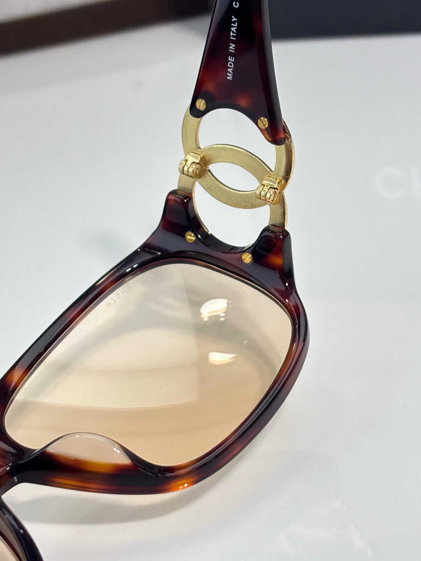 Chanel glasses close-up of tortoiseshell frame with gold-tone ring detail and amber lens