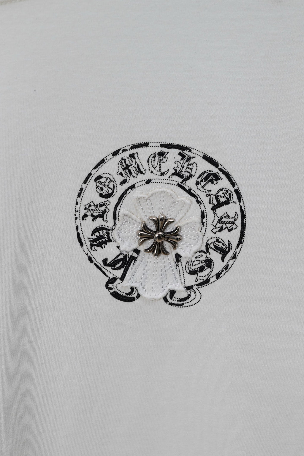 Small circular emblem graphic on a white chrome short T-shirt