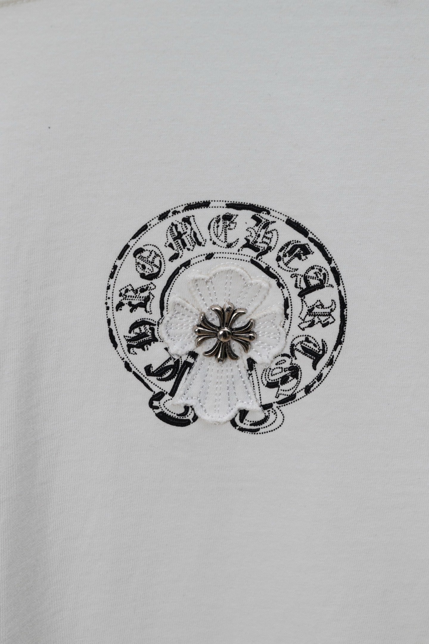 Small circular emblem graphic on a white chrome short T-shirt